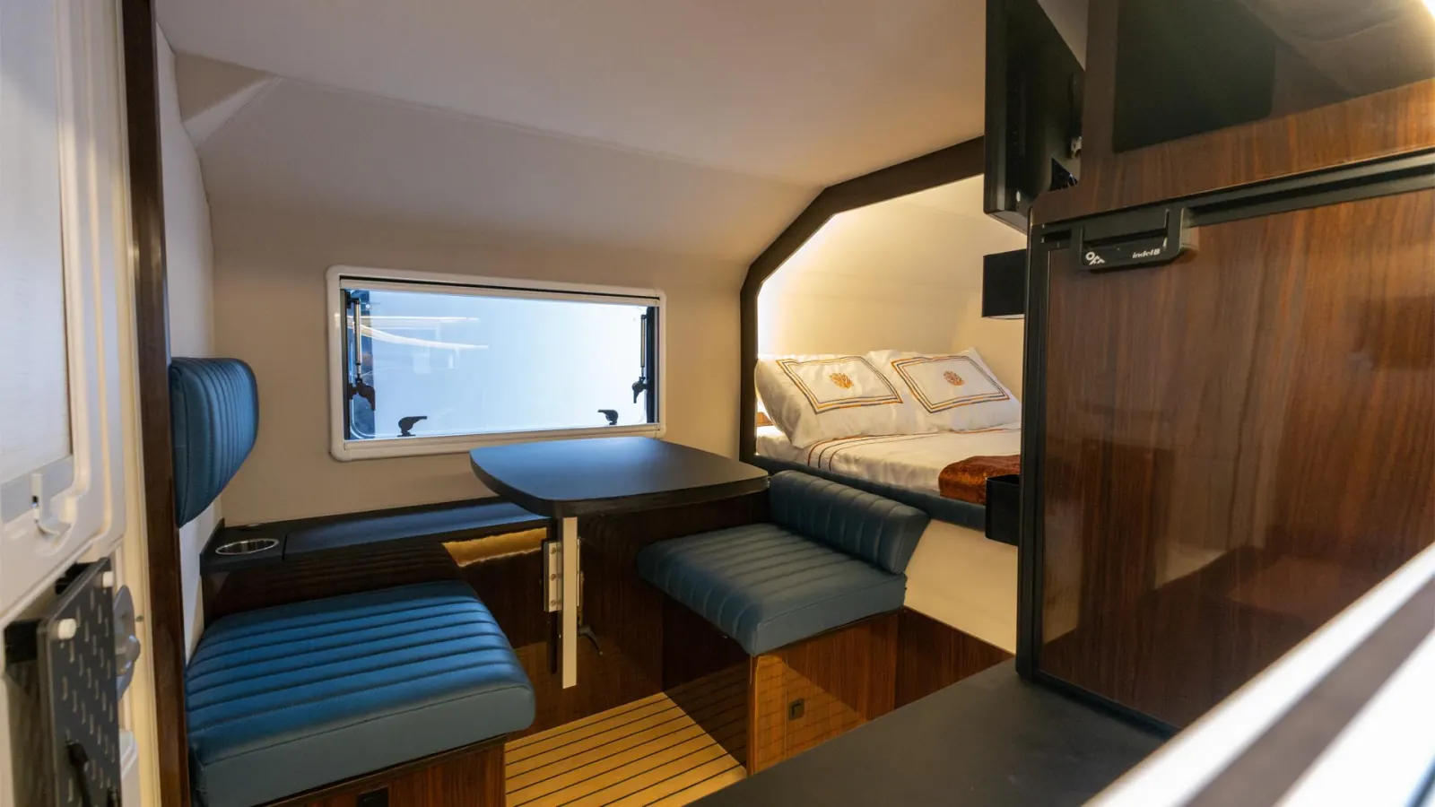 Cyberglad: two facing seats and a table, the bed beyond