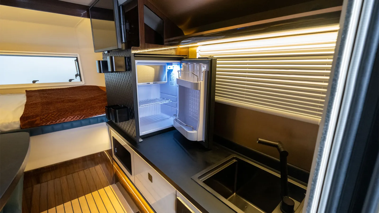Cyberglad: kitchen with sink and the 42 L fridge open, bed behind